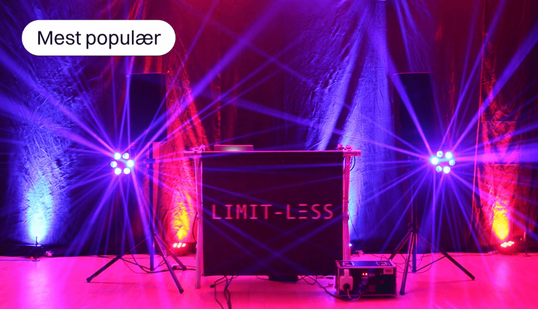 DJ setup with colorful stage lights and 'Limit-Less' sign on the booth.