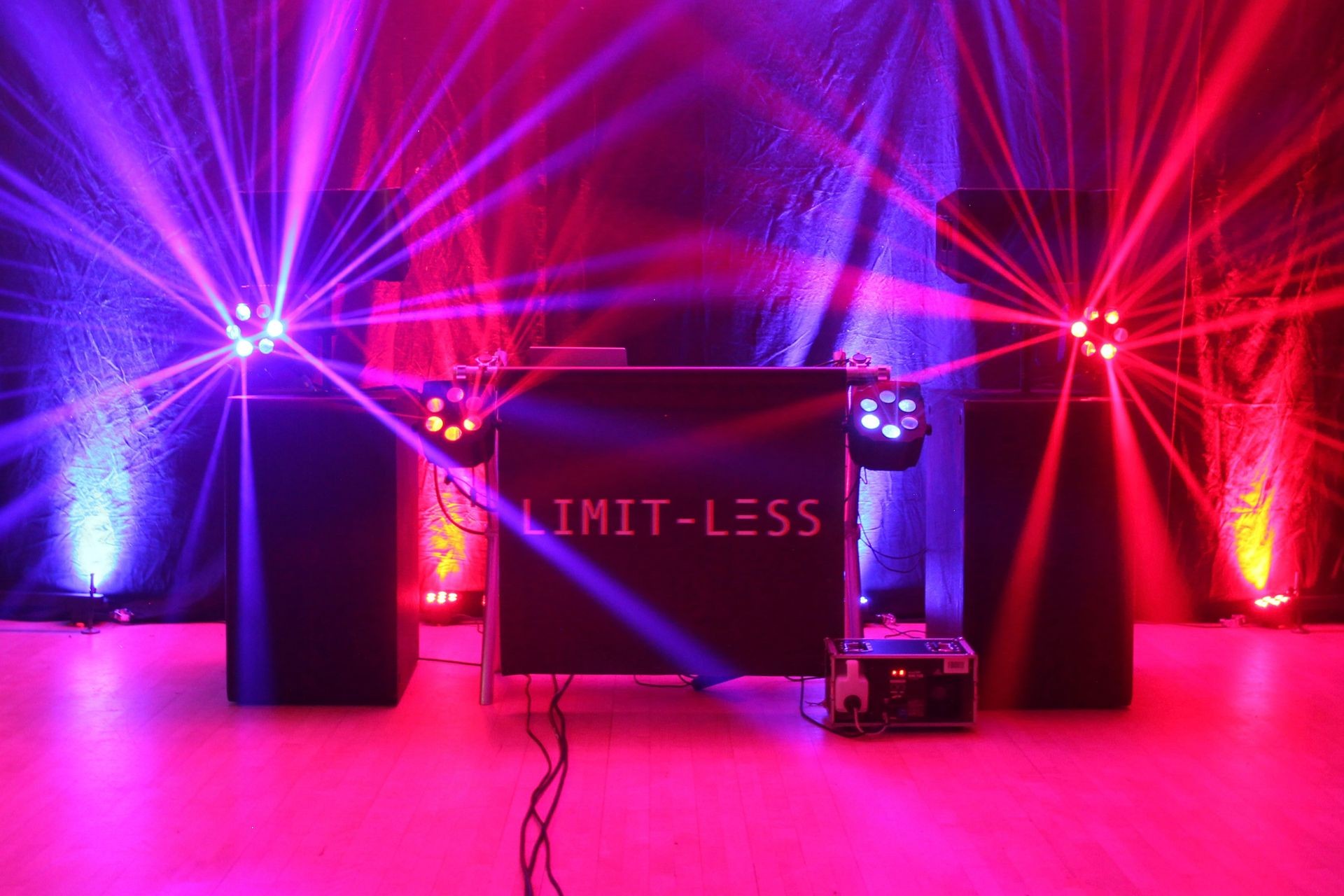 Stage setup with vibrant purple and red lights and a sign reading 'LIMIT-LESS'.