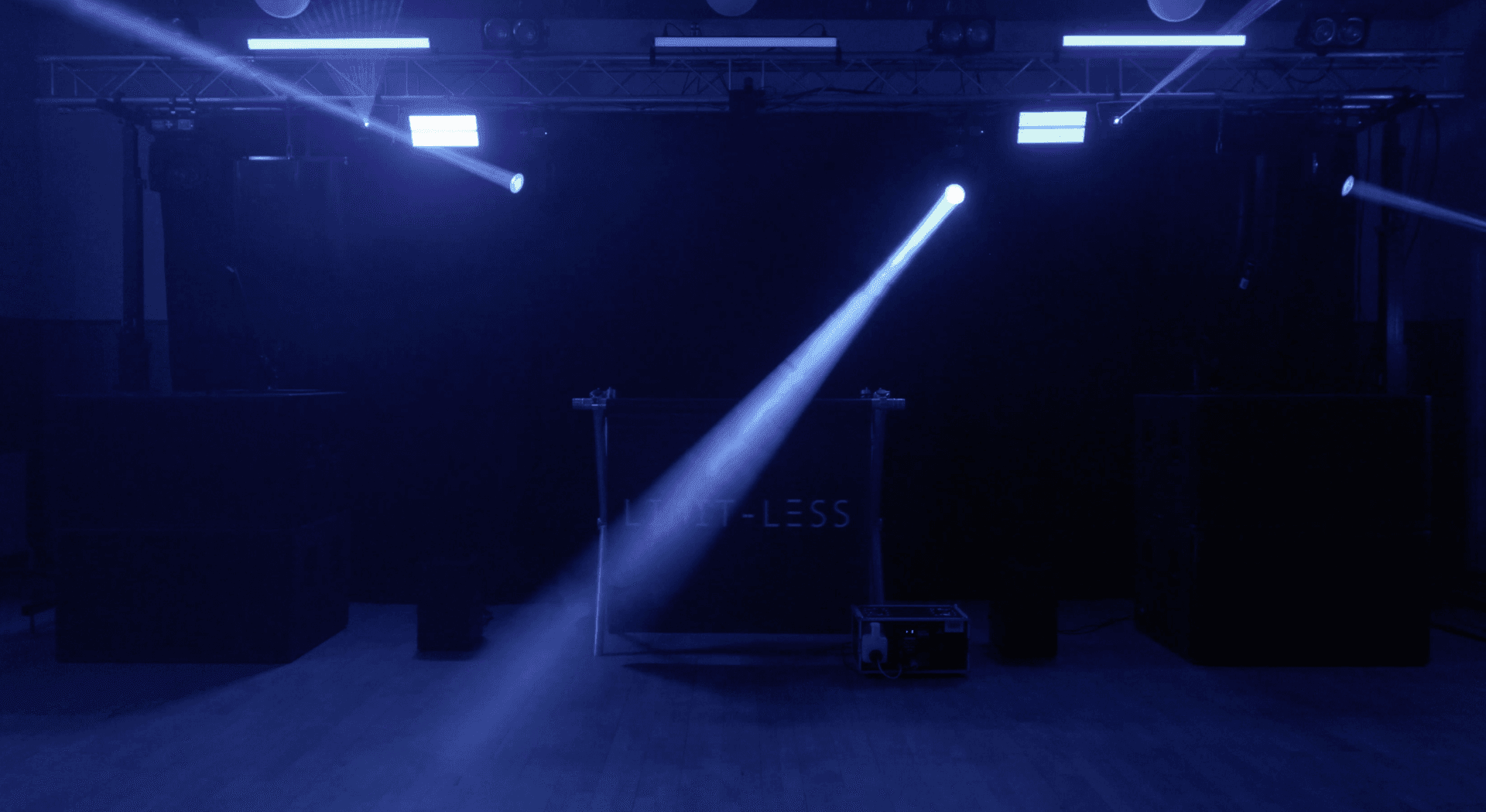 Dark stage with blue spotlights and audio equipment, creating a moody atmosphere.