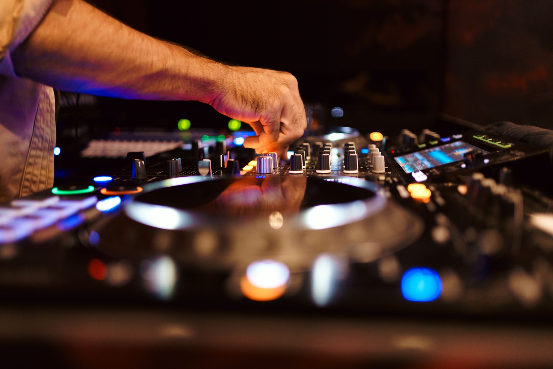 Close up DJ plays live set and mixing music on turntable console in the night club. Disc Jokey Hands on a sound mixer station at club party. DJ mixer controller panel for playing music and partying.
